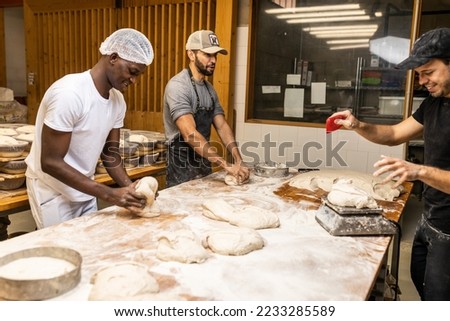 Multi-ethnic group of colleagues working in a bread factory, teaching the apprentices