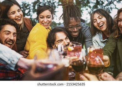 Multiethnic group of excited young people having fun toasting wine and beers together at terrace birthday party - lifestyle concept of multigenerational diverse family stay together - focus center man - Powered by Shutterstock