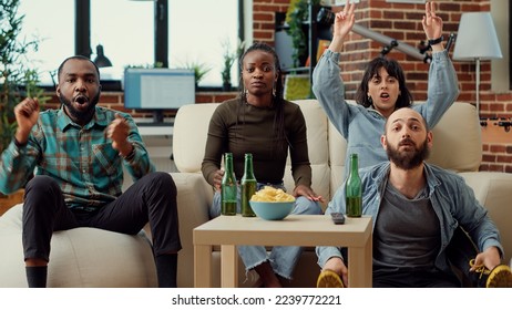 Multiethnic group of football fans watching soccer match and drinking beer, cheering to score goal and win championship. People enjoying sport competition on television. Tripod shot. - Powered by Shutterstock