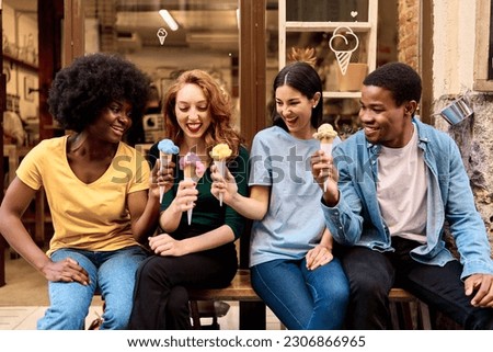Multiethnic group of friends celebrating while eating ice cream outdoors