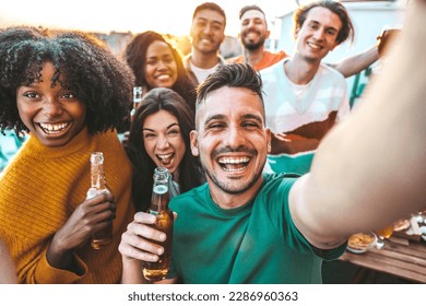 Multiethnic group of friends hanging out on a dinner rooftop party - Multiracial young people having fun enjoying together summertime days - Life style concept with guys and girls laughing outside 