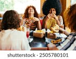 Multiethnic group of friends having meal at 80s vintage diner restaurant - Multiracial young people bonding and having fun, eating in an american fast food burger house