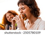 Multiethnic group of friends having meal at 80s vintage diner restaurant - Multiracial young people bonding and having fun, eating in an american fast food burger house