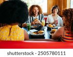 Multiethnic group of friends having meal at 80s vintage diner restaurant - Multiracial young people bonding and having fun, eating in an american fast food burger house