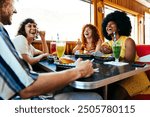 Multiethnic group of friends having meal at 80s vintage diner restaurant - Multiracial young people bonding and having fun, eating in an american fast food burger house