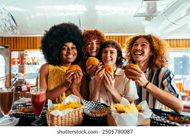 Multiethnic group of friends having meal at 80s vintage diner restaurant - Multiracial young people bonding and having fun, eating in an american fast food burger house - Powered by Shutterstock