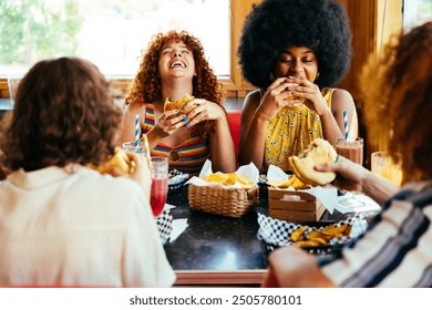 Multiethnic group of friends having meal at 80s vintage diner restaurant - Multiracial young people bonding and having fun, eating in an american fast food burger house - Powered by Shutterstock