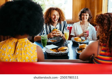 Multiethnic group of friends having meal at 80s vintage diner restaurant - Multiracial young people bonding and having fun, eating in an american fast food burger house - Powered by Shutterstock