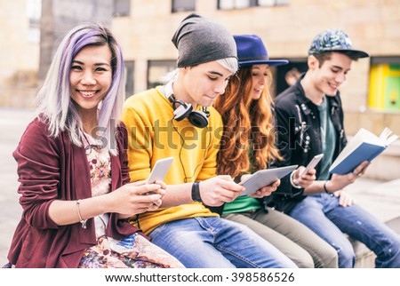 Multiethnic group of friends looking down at phone and tablet, concepts about technology addiction and youth