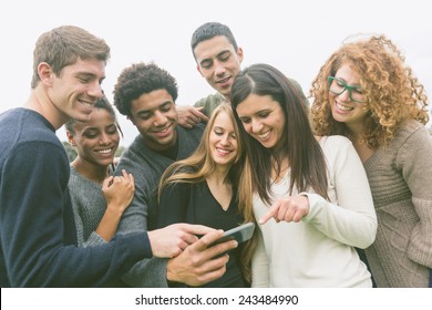 Multiethnic Group Of Friends Looking At Mobile Phone