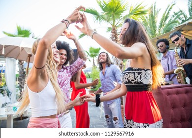 Multiethnic group of friends making party in a lounge bar - Cheerful young adults having fun and celebrating outdoors - Shutterstock ID 1129567916