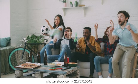 Multi-ethnic group of friends sports fans with Brazilian flags watching football championship on TV together at home indoors and cheering up favourite team - Shutterstock ID 2175715541