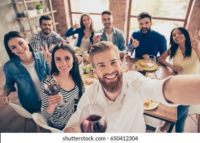Multiethnic group. Handsome bearded guy is making selfie with his friends at the party on his phone`s camera. Everyone are smiling and and enjoying their company, having fun