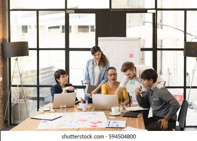 Multi-ethnic Group Of Happy Business People Working Together, Meeting And Brainstorming In Office. Use Computer, Laptop, Tablet, Mobile Phone.