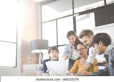 Multiethnic Group Of Happy Business People Working Together, Meeting And Brainstorming In Office. Use Computer, Laptop, Tablet, Mobile Phone.