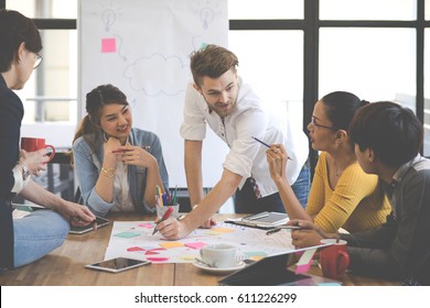 Multiethnic group of happy business people working together, meeting and brainstorming in office. Use computer, laptop, tablet, mobile phone. - Shutterstock ID 611226299
