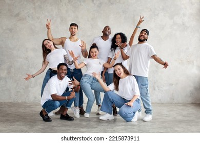 Multiethnic group of happy friends smile and raise hands up. Diverse young people standing together in white shirts and jeans on background wall in studio - Powered by Shutterstock