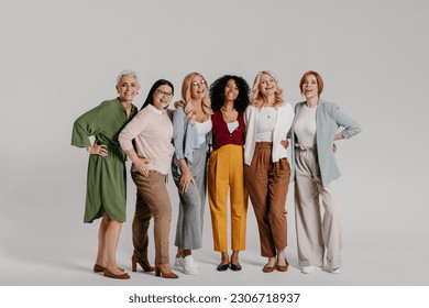 Multi-ethnic group of happy mature women bonding against grey background - Powered by Shutterstock