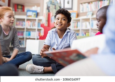 Multiethnic group of kids sitting on floor in circle around the teacher and listening a story. Discussion group of children inaa library talking to woman. Smiling hispanic boy in elementary school. - Shutterstock ID 1086016097