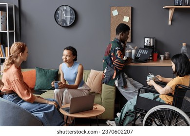 Multiethnic group of modern young people relaxing at coffee station in office in break lounge - Powered by Shutterstock