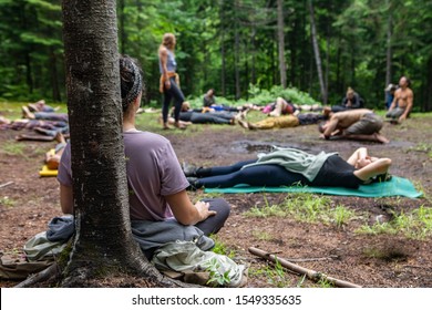 A Multiethnic Group Of People Of All Ages Are Seen Seeking Enlightenment And Mindfulness As They Meditate In A Forest Clearing During A Spiritual Retreat.