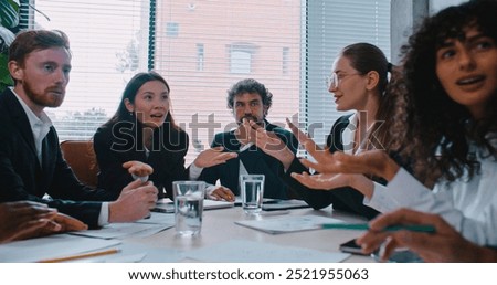 Multi-ethnic group of people arguing during important meeting. Man in middle sitting silently and spectating. Problems at company. Difficult decision. People not agreeing. Problems in office.