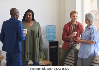 Multi-ethnic Group Of People Drinking Coffee And Chatting While Standing By Water Cooler In Support Meeting, Copy Space