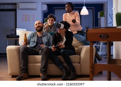 Multiethnic Group Of People Having Fun With Video Games On Console And Virtual Reality Glasses. Coworkers Meeting At Office Party Celebration With Beer Drinks After Work Hours.