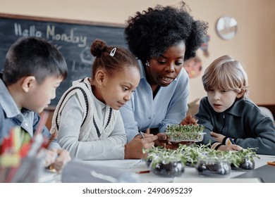 Multiethnic group of primary school kids discovering growth of plants looking at microgreen sprouts during biology lesson - Powered by Shutterstock