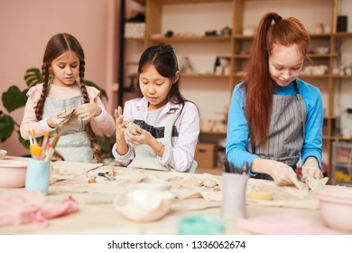 Multi-ethnic Group Of Schoolchildren Making Handmade Ceramics In Pottery Class