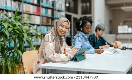 Multiethnic group of students sitting in a library and studying together
