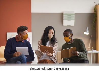 Multi-ethnic Group Of Three Business People Wearing Face Masks While Discussing Project In Office