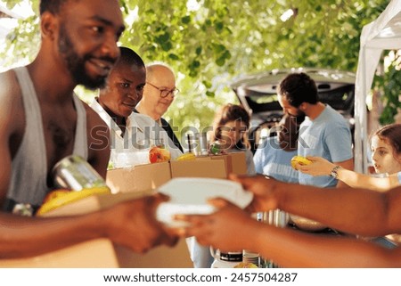 Multiethnic group of volunteers providing humanitarian aid to homeless people. They distribute meal boxes canned goods and packages with genuine smiles helping to alleviate poverty and hunger.