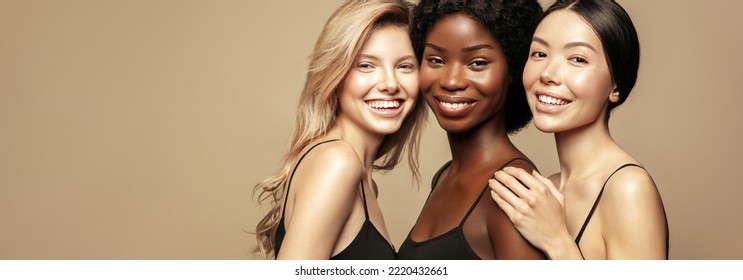 Multi-Ethnic Group of women with different types of skin together against a beige background. Diverse ethnicity women - Caucasian, African and Asian.
