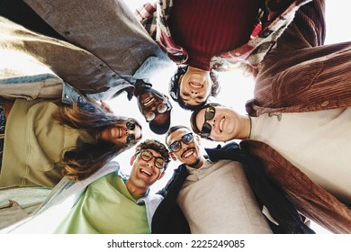 Multiethnic group of young friends joining heads in circle watching down to the camera - international youth culture concept with different people enjoining life together - people lifestyle concept - Shutterstock ID 2225249085