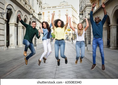 Multi-ethnic Group Of Young People Having Fun Together Outdoors In Urban Background. Group Of People Jumping Together