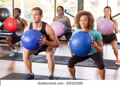 Multi-ethnic gym class doing squats with medicine balls - Powered by Shutterstock