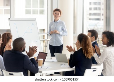 Multiethnic happy employees applaud thanking female speaker for successful flip chart presentation, excited diverse work group clap hands show gratitude to smiling woman coach seminar or training - Powered by Shutterstock