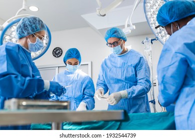 Multi-ethnic healthcare workers performing surgery on patient at operation theater. Medical colleagues operating in emergency room at hospital. They are in scrubs - Shutterstock ID 1932544739