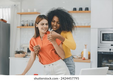 Multiethnic lesbian couple having embracing in kitchen room. black and white couple holding ring. positive African American and white lesbian couple hugging and looking at each other with tenderness - Powered by Shutterstock