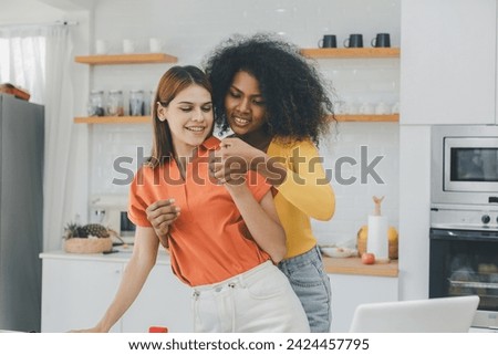 Multiethnic lesbian couple having embracing in kitchen room. black and white couple holding ring. positive African American and white lesbian couple hugging and looking at each other with tenderness