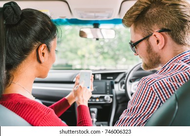 Multiethnic Lover Couple, White Man And Black Asian Girl Using Navigator System App On Smart Phone In Car. Modern Gadget Lifestyle, Family Travel Activity, Or Online Taxi Call Request Service Concept.