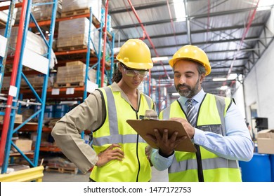 Multi-ethnic male and female staff discussing over clipboard in warehouse. This is a freight transportation and distribution warehouse. Industrial and industrial workers concept - Powered by Shutterstock