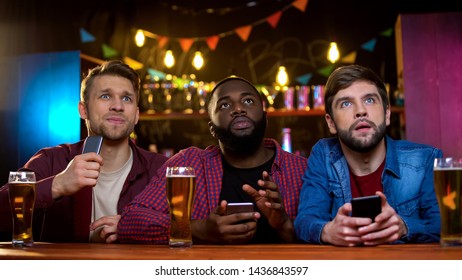 Multiethnic Male Friends Watching Football Match In Pub, Upset With Team Losing