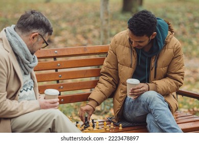 Multi-ethnic men playing chess in autumn park on a bench. - Powered by Shutterstock