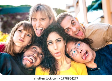 Multiethnic milenial people taking selfie sticking out tongue with happy faces - Funny life style and integration concept with interracial young friends having fun together - Vivid backlight filter - Powered by Shutterstock