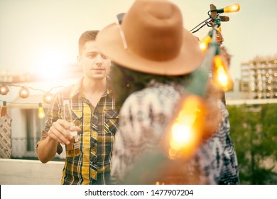 Multi-ethnic Millenial Couple Flirting While Having A Drink On Rooftop Patio At Sunset