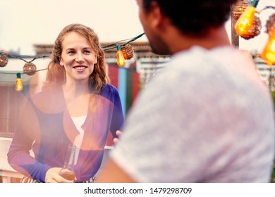 Multi-ethnic Millenial Couple Flirting While Having A Drink On Rooftop Patio At Sunset