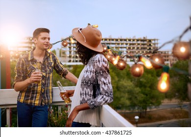 Multi-ethnic Millenial Couple Flirting While Having A Drink On Rooftop Terrasse At Sunset