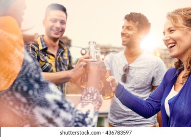 Multi-ethnic Millenial Group Of Friends Partying And Enjoying A Beer On Rooftop Terrasse At Sunset